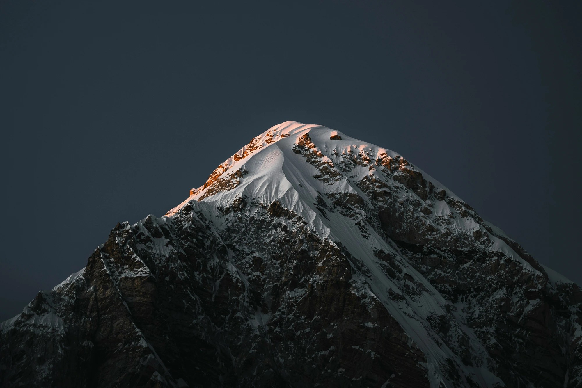 Berggipfel im ersten Licht über weitläufiger Berglandschaft